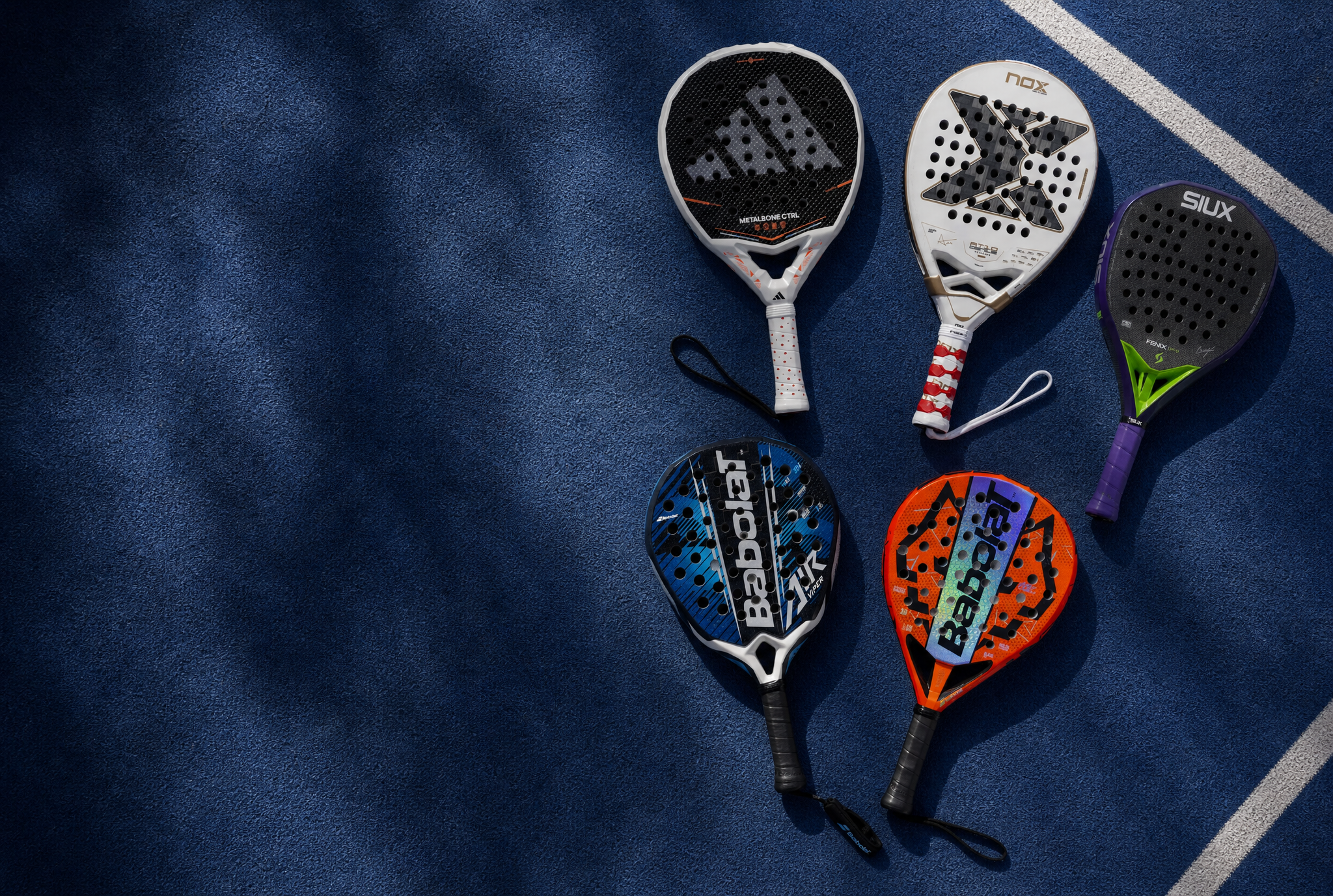Five padel rackets on a blue surface with visible brand logos.