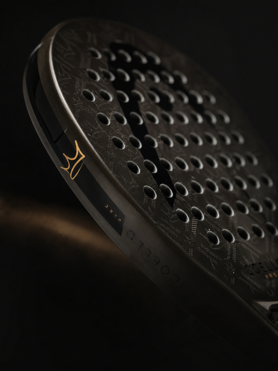 Close-up of a textured black padel with a brand logo on a dark background